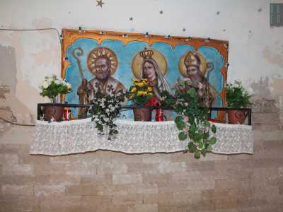 All'ombra di un arco in un vicolo del centro storico, un colorato affresco ritrae una Madonna affiancata da due santi